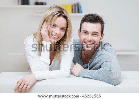 Young happy couple smiling together at camera in their home