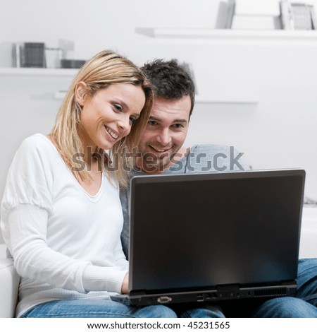 Young happy couple surfing the net with their laptop at home