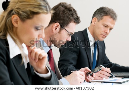Absorbed businessman looking at his pda organizer during a meeting with colleagues in office