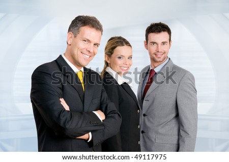 Three happy business colleagues standing together and looking at camera in their modern office