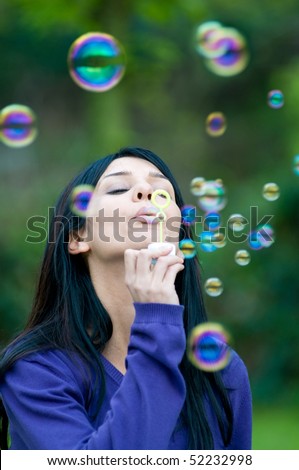 Young beautiful girl blowing bubbles in the nature, symbol of hope and aspirations