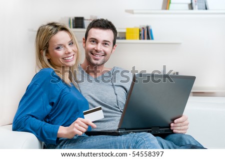 Smiling young couple making shopping online with credit card and laptop at home