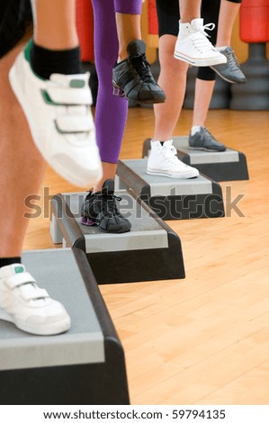 Detail of raised feet during aerobic step exercise at gym