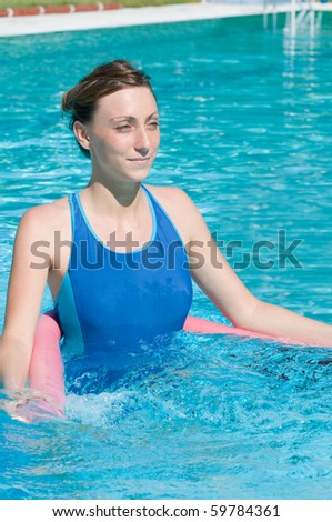 Happy young woman doing aqua gym exercise in swimming pool