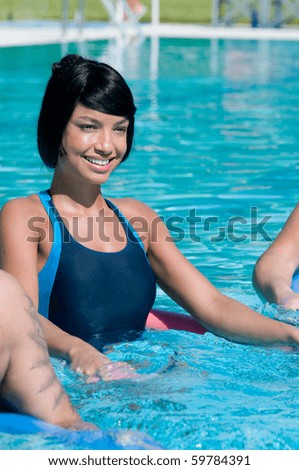 Young beautiful latin woman doing aqua gym exercise in a swimming pool