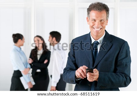 Happy smiling mature businessman receiving positive news on his smart phone at office