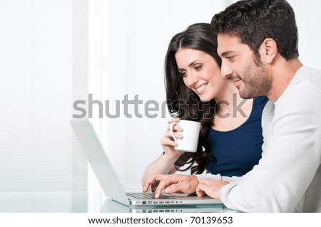 Happy modern couple surfing the net and working on laptop at home Happy modern couple surfing the net and working on laptop at home