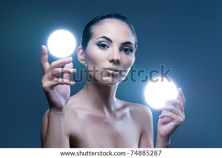 Beautiful fairy female model holding two spheres of light on her hands, professional beauty makeup