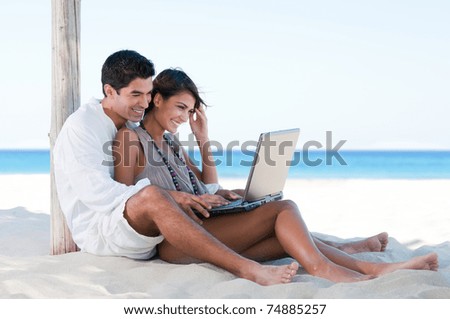 Happy smiling couple surfing the net and enjoy the summer at tropical beach Happy smiling couple surfing the net and enjoy the summer at tropical beach