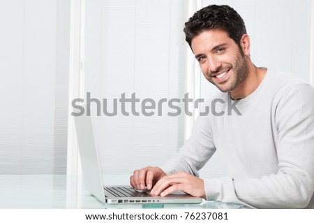 image: stock-photo-happy-satisfied-young-man-working-on-laptop-and-looking-at-camera-76237081