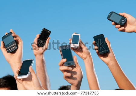 Happy people showing their modern mobile phones against blue sky