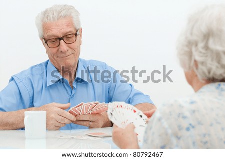 Happy old couple playing together with  cards at home