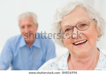 Happy senior woman smiling with her husband on background