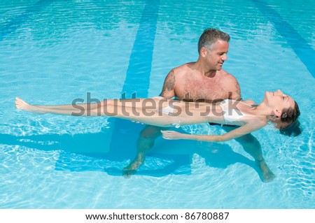 Personal trainer give first lesson of swimming to a young lady in a swimming pool