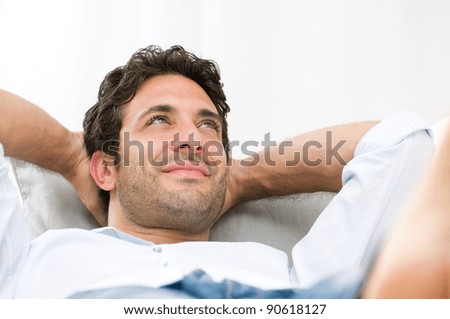 Serene happy man relaxing on sofa at home