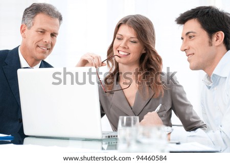 Happy businesswoman looking at coputer with her business colleagues at office