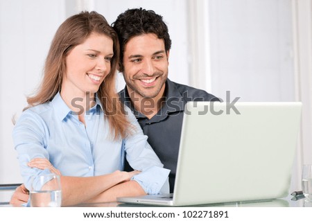 Happy smiling young couple watching together at computer laptop