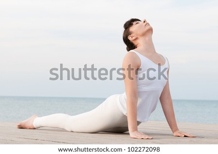 Young healthy woman doing yoga position at sea: Cobra pose