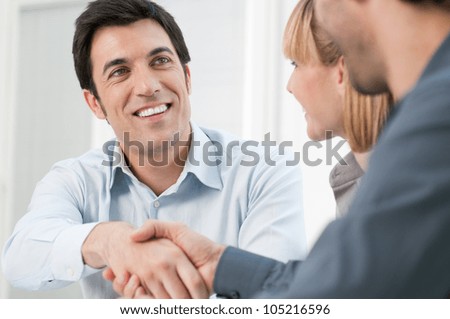 Happy smiling business man shaking hands after a deal in office