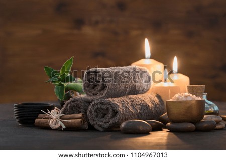 Brown towels with bamboo and candles for relax spa massage and body treatment. Composition with candles, spa stones and salt on wooden background. Spa and wellness setting ready for beauty treatment.