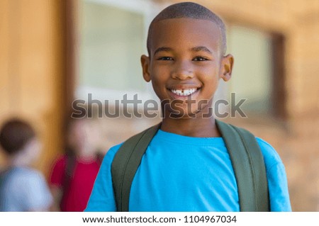 Smiling african american school boy with backpack looking at camera. Cheerful black kid wearing green backpack with a big smile. Elementary and primary school education.