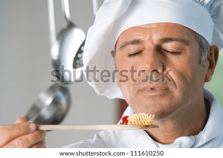 Mature satisfied chef smell the aroma of his food while cooking at restaurant