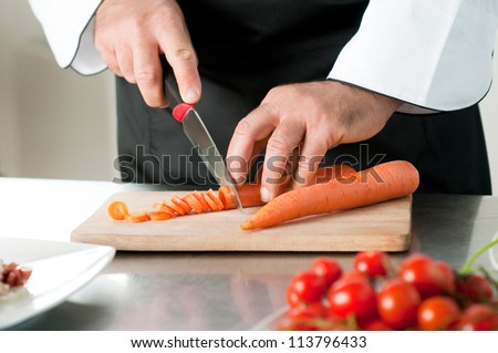 Cutting carrot on a wooden board for meal preparation at restaurant