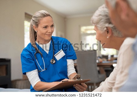 Happy nurse talking to senior patients in private clinic. Senior couple consulting health and medical report with doctor at home. Old man and elderly woman visiting the nurse with clipboard.