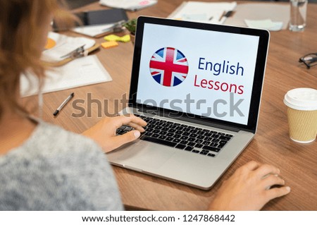Mature woman learning English online with computer. Laptop screen of woman displaying english lessons poster with British flag. Closeup of student using laptop doing online course on english.