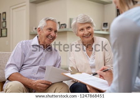 Senior couple meeting real estate agent at home. Old husband and wife with financial advisor for investment opportunities. Happy elderly man and woman listening to various investment plans.