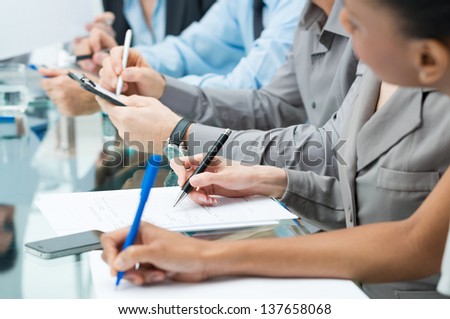 Close-up Of A Business People Hands Writing Note During Meeting