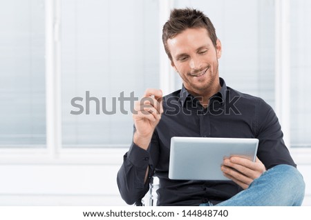 Portrait Of A Handsome Young Happy Man Using Digital Tablet