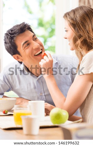 Happy Young Woman Feeding Strawberry To Man