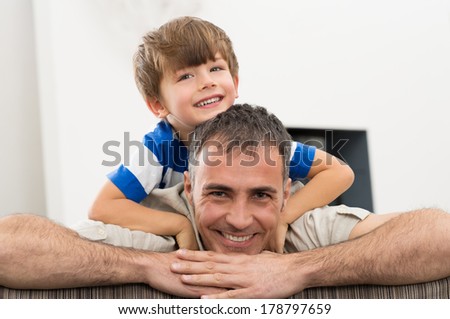 Portrait Of Happy Father Carrying His Son A Piggyback Ride