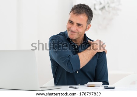 Portrait Of Mature Man At Work Suffering From Shoulder Pain