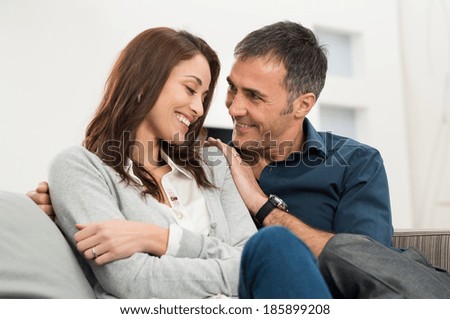 Portrait Of Happy Loving Couple Sitting On Couch At Home
