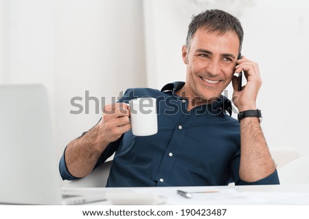 Portrait Of Smiling Mature Man Talking On Cellphone Holding Coffee Cup