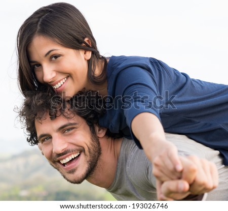 Young Happy Man Giving Piggyback Ride To Smiling Woman