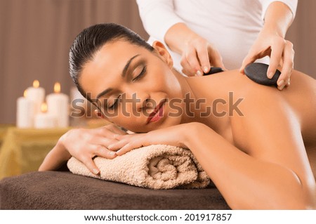 Beautiful Young Woman Receiving Hot Stones Massage At Day Spa