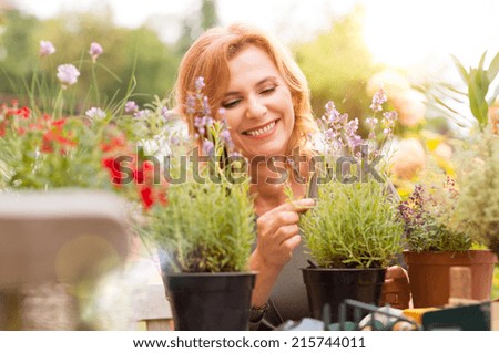 Portrait Of Happy Mature Woman Arranging Plants In Garden