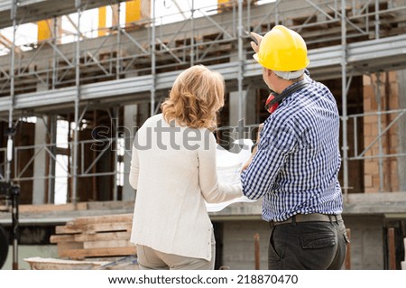 Rear View Of Male Architect And Client Looking At Under Construction Building