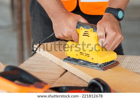 Closeup Of Carpenter Hand Sanding Plank With Electrical Sanding Machine