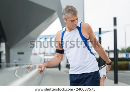 Portrait Of Mature Male Jogger Stretching His Leg In A City