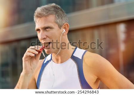 Portrait Of Fitness Mature Man Eating A Energy Bar Of Chocolate