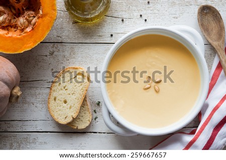 Cream of vegetarian pumpkin soup with bread on wooden table