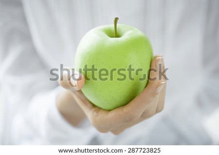 Closeup shot of a woman holding healthy green apple. Girl with a green apple in hands. Shallow depth of field with focus on the green apple.