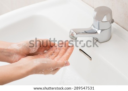 Closeup shot of a woman washing hands with soap lather over bathroom sink. Girl cleaning hand.