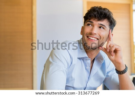 Closeup shot of young man smiling and looking up. Handsome young man smiling and looking away. Portrait of man thinking and imaging. Contemplative man with shirt thinking and smiling about the future.
