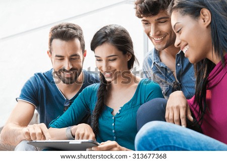 Closeup shot of young men and women looking at digital tablet. Happy smiling group of friends sitting outdoor using digital tablet. \
 Happy young woman pointing on a digital tablet.
