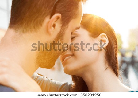 Closeup shot of young couple kissing outdoor. Close up of loving couple embracing and kissing. Shallow depth of field with focus on young couple kissing.